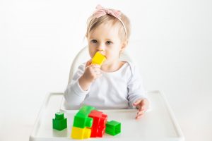 One year old child sitting at table with colourful blocks