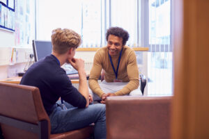 A young male student talking and smiling with a young male counsellor