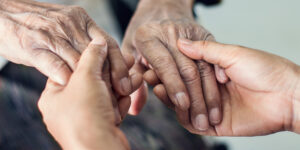 Younger hands holding the hands of an elderly person, perhaps to sooth or help them up