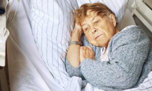an elderly woman lying in a hospital bed looking sad and alone